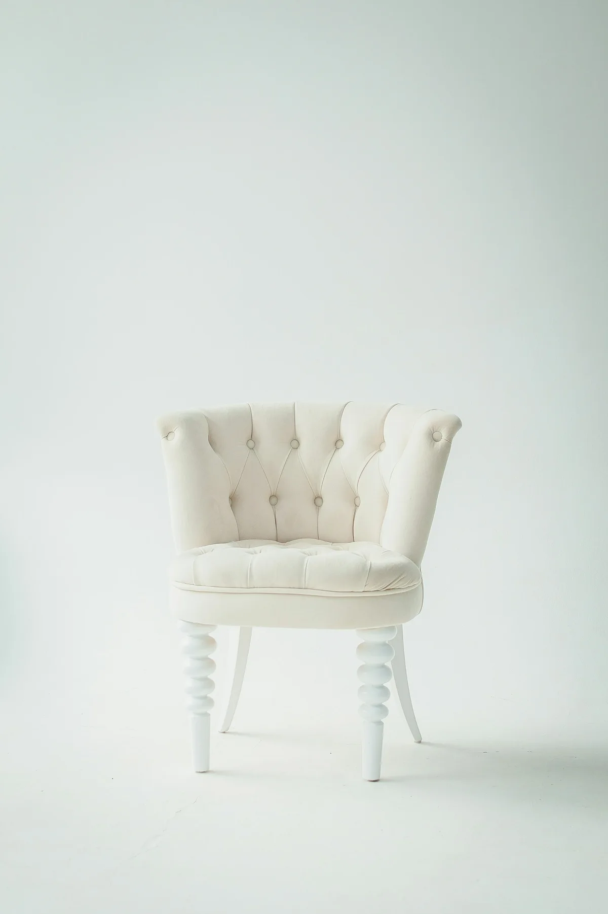 Cream upholstered occasional chair with a curved back and turned legs