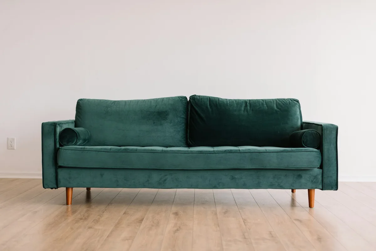 Deep green upholstered sofa with timber legs